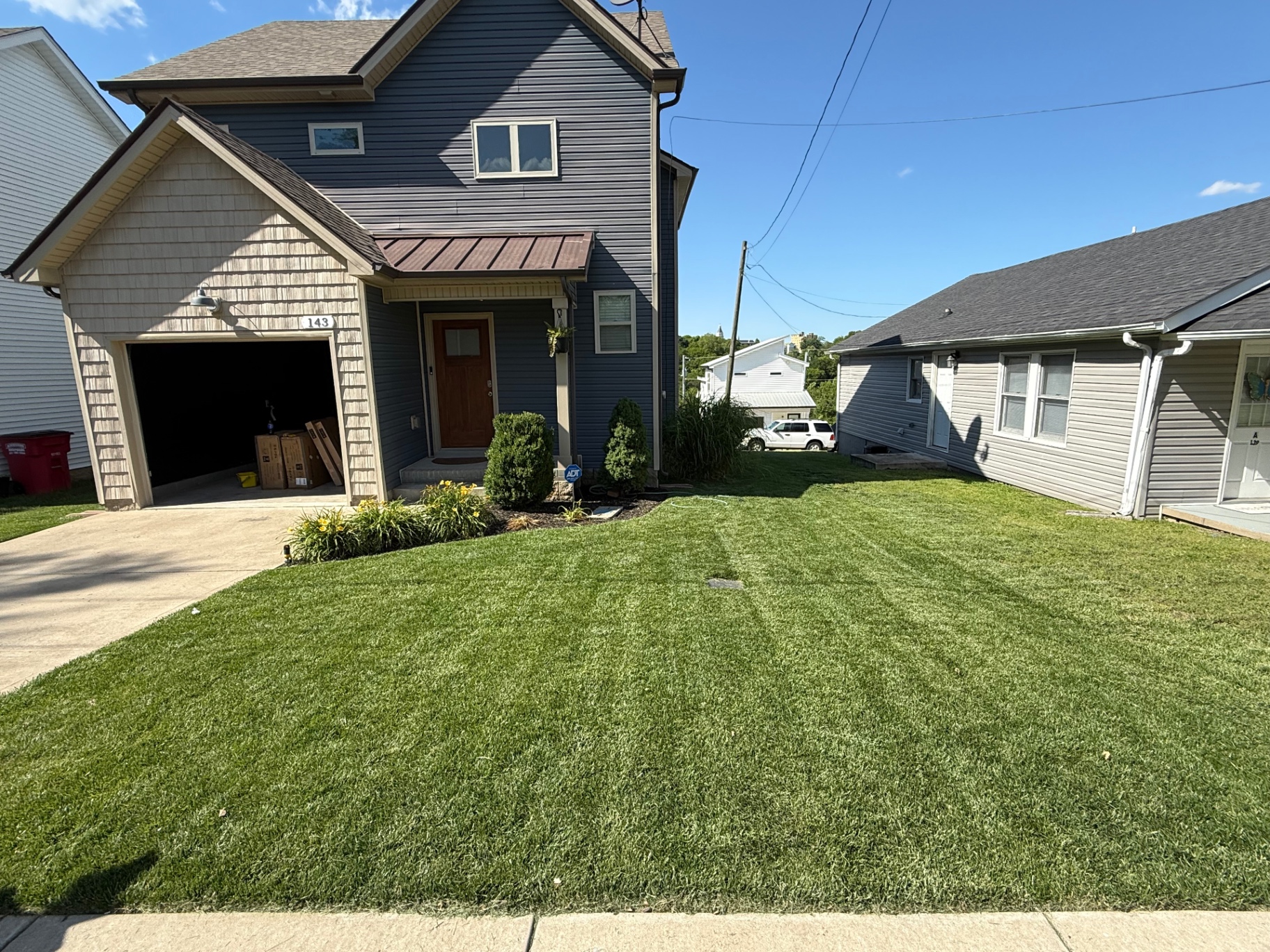 Freshly mowed striped lawn in front of a blue two-story home