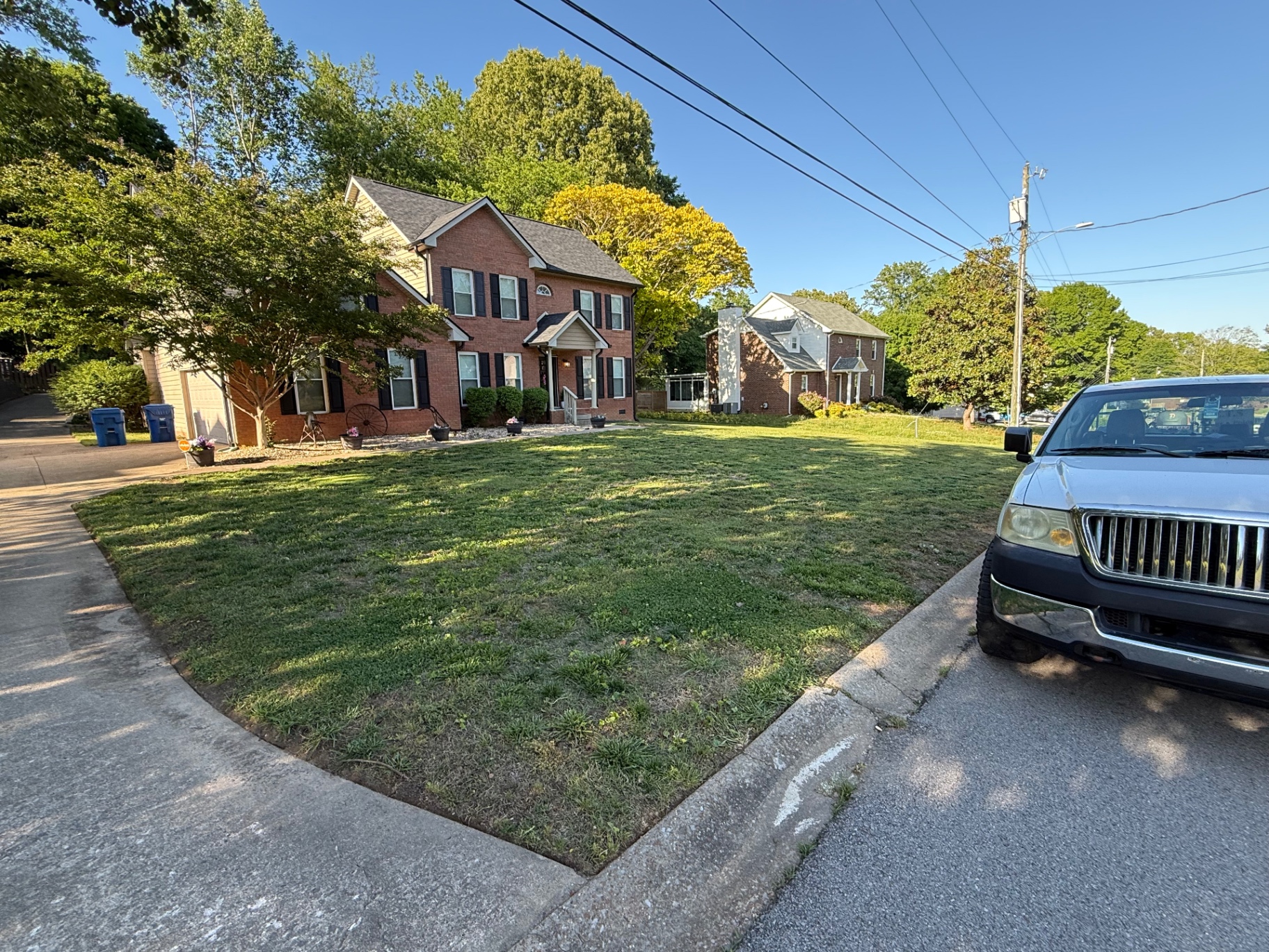 Trimmed corner-lot lawn at a brick colonial home