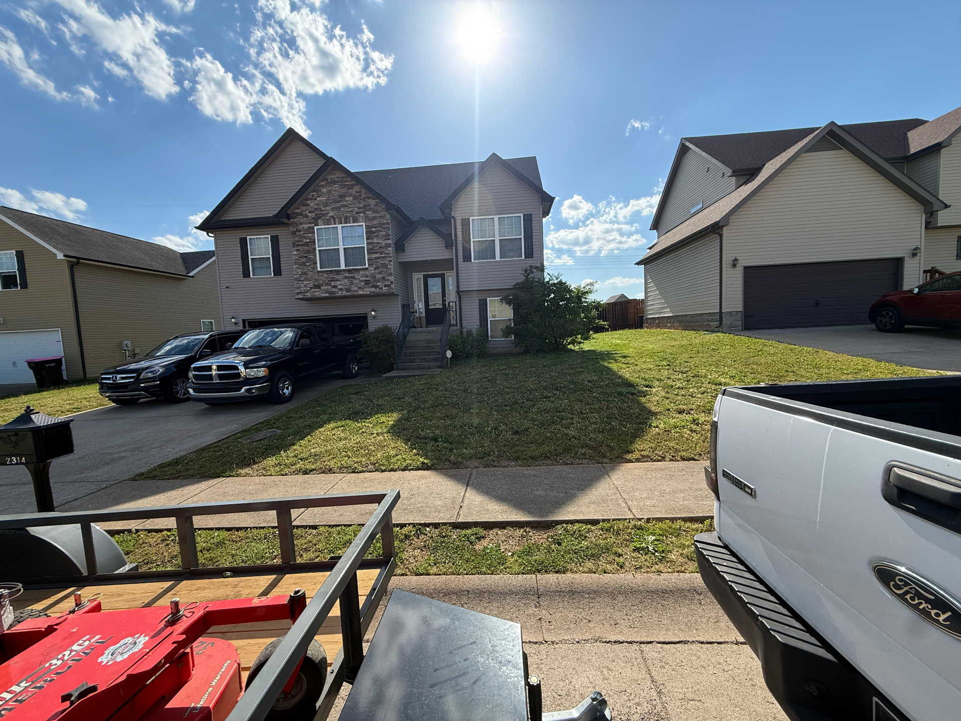 Mowed front yard with mower and truck on the curb