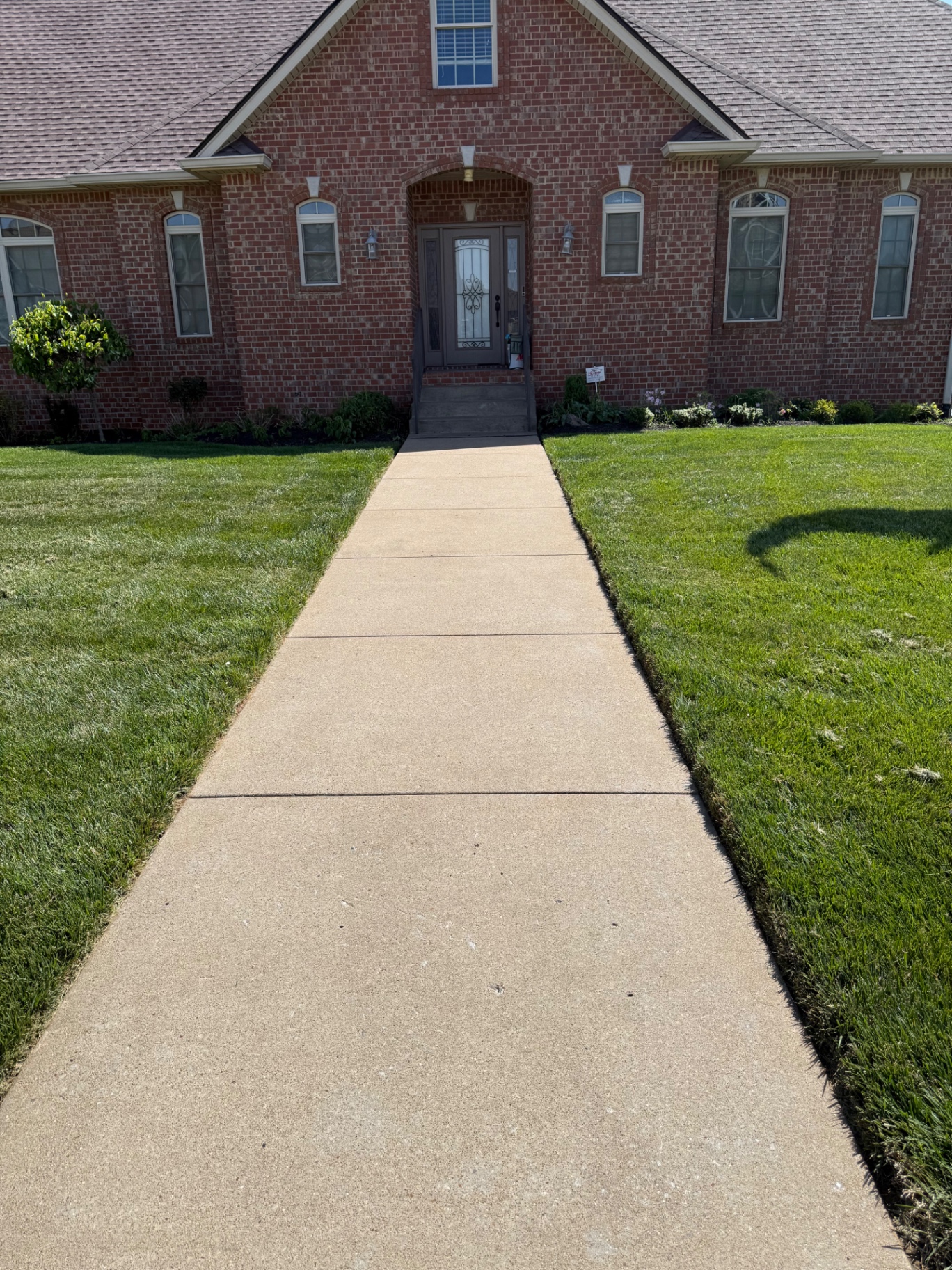 Crisp edged walkway with manicured lawn at a brick home