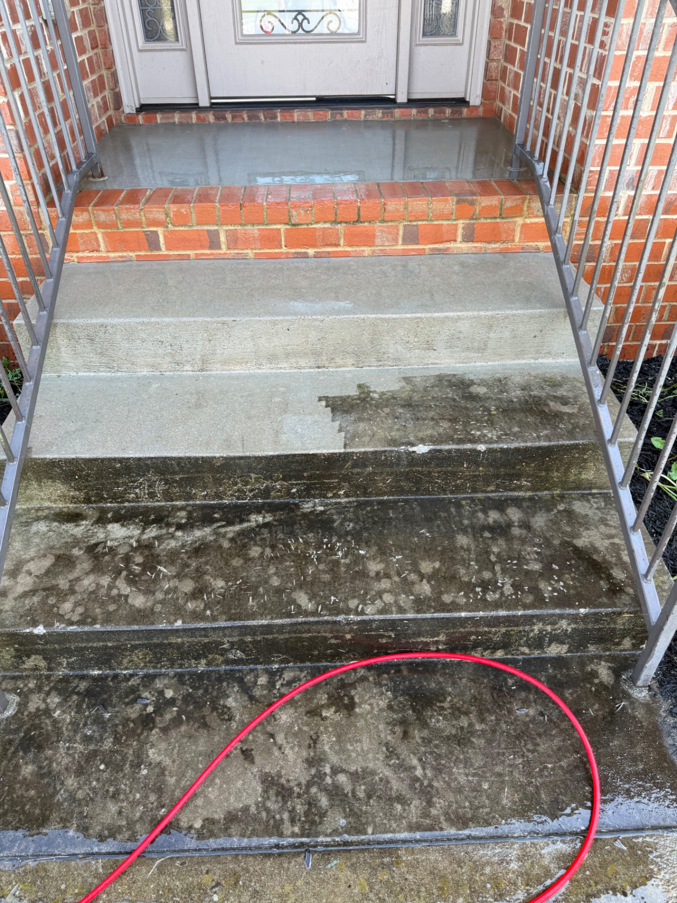 Pressure washing in progress on brick front steps showing clean vs dirty contrast